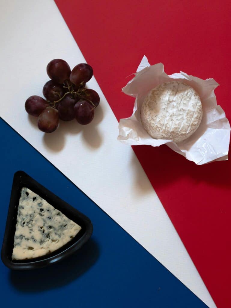 Delicious French cheese and grapes atop a French flag-inspired backdrop.