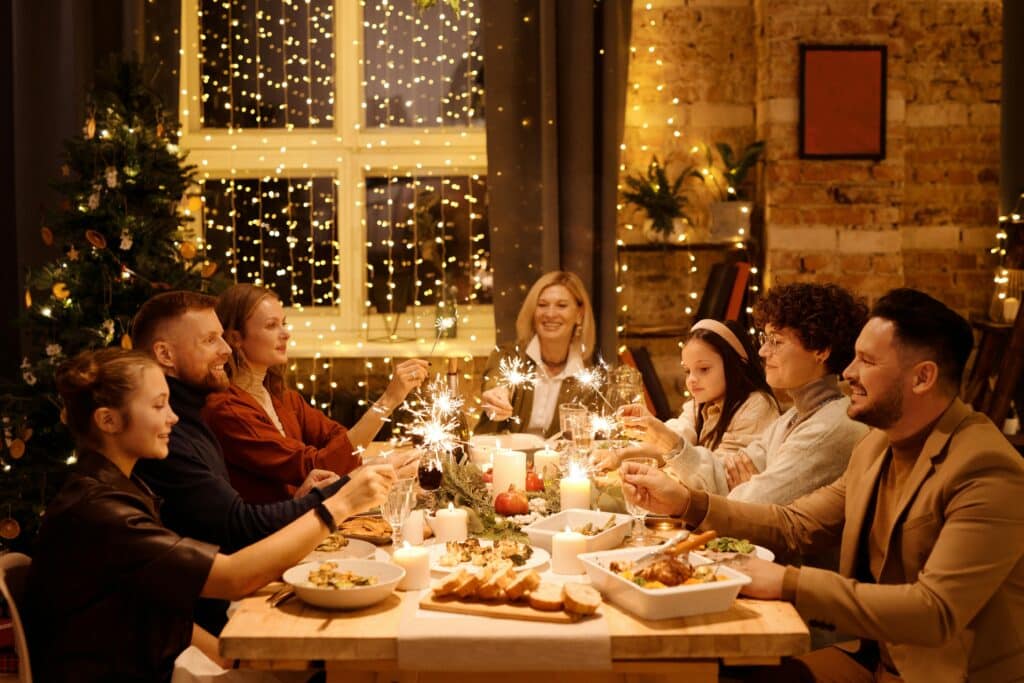 Family celebrating Christmas with dinner and sparklers, creating joyful holiday atmosphere indoors.